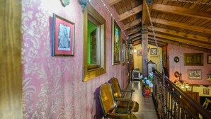 A hallway with wooden chairs, framed pictures on the walls, and a staircase with a wooden railing.