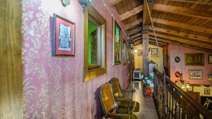 A hallway with wooden chairs, framed pictures on the walls, and a staircase with a wooden railing.