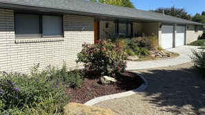 A single-story brick house with a covered porch, a driveway, and a landscaped garden with various plants and a rock feature. - Perfect for Long Stays. Recently remodeled townhouse next to Freeway & C of I.  (Caldwell)