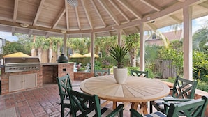 Une terrasse extérieure équipée d’un barbecue, de sièges et d’un ventilateur de plafond.