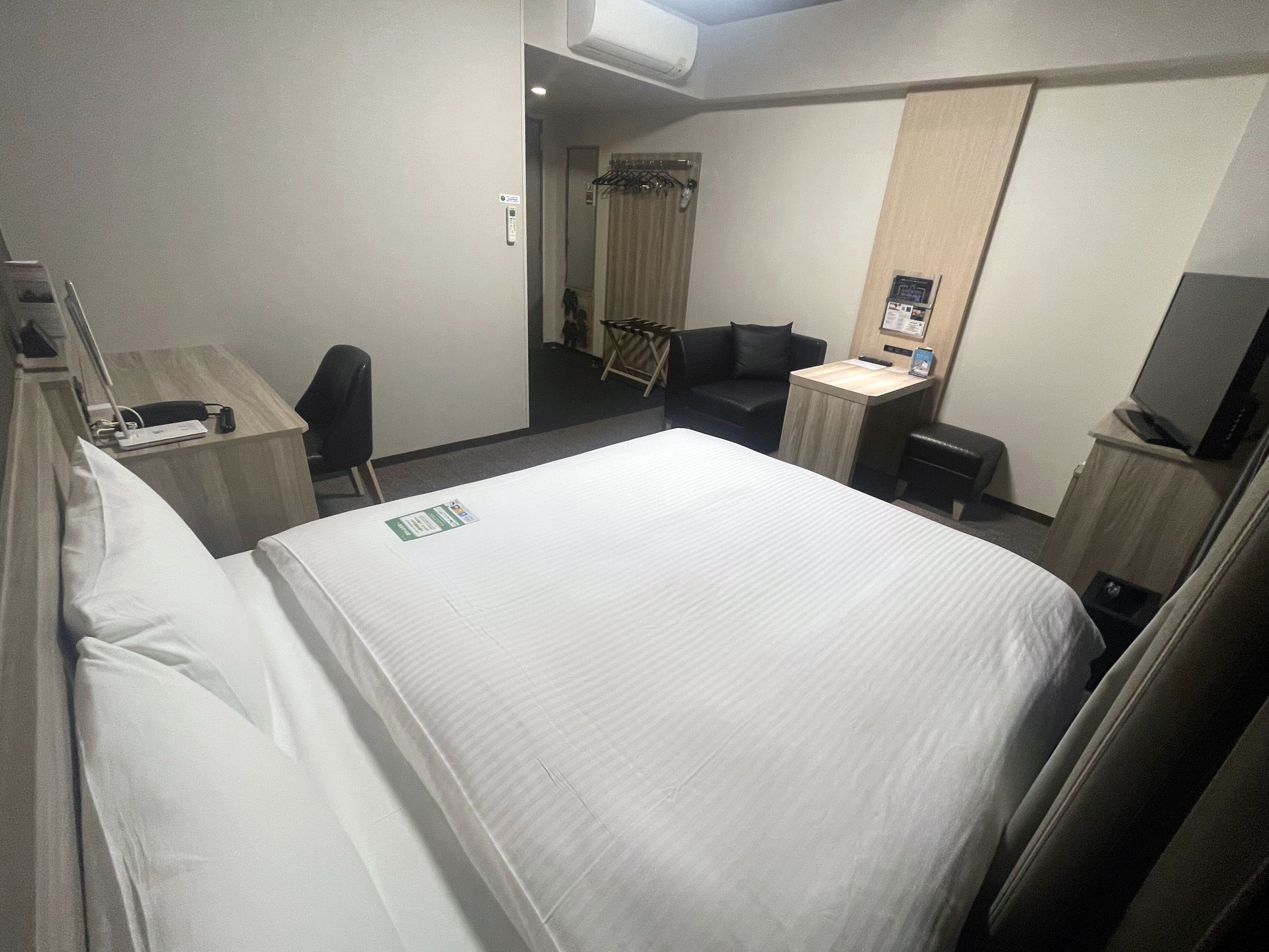 Een hotelkamer met een groot bed, een bureau met stoel, een televisie en een kleine tafel.