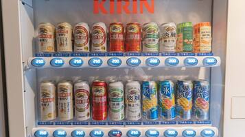 Máquina automática de bebidas com diversas opções, incluindo cerveja Kirin e outras bebidas, com etiquetas de preço e botões de seleção.