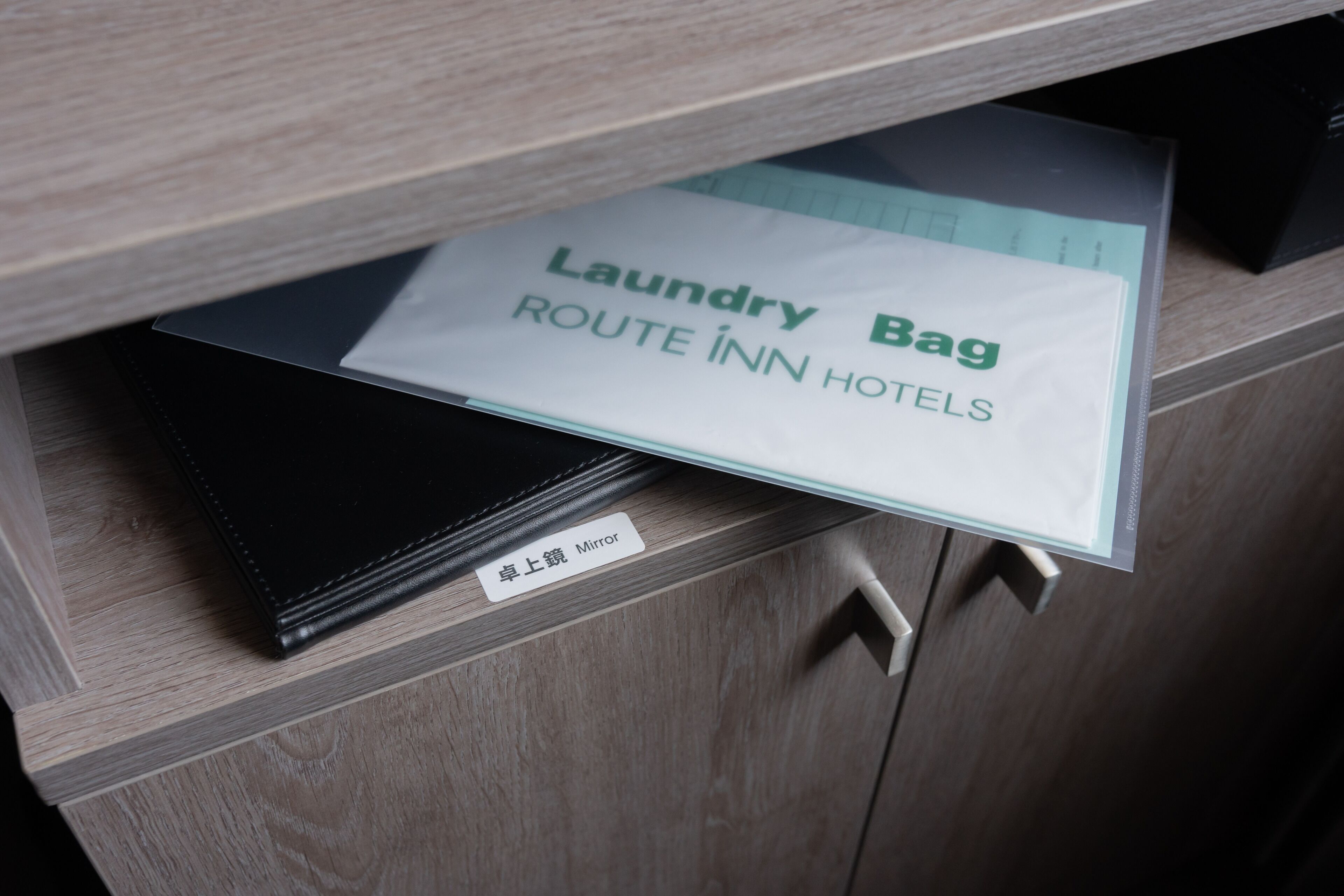 A drawer with a 'Laundry Bag' and a 'Mirror' label, indicating amenities in a hotel room.