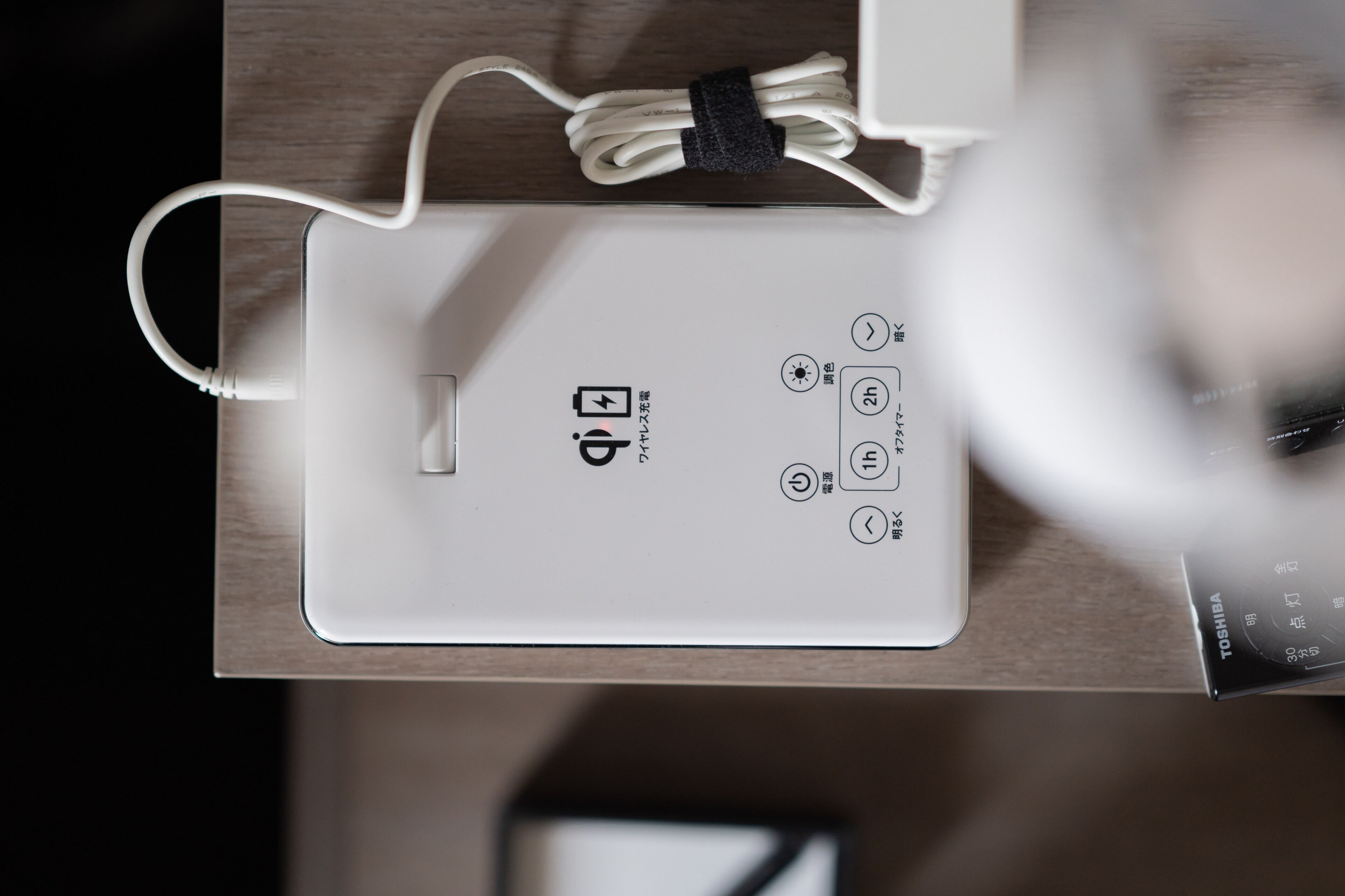 Een wit elektronisch apparaat met een USB-poort en aan/uit-knoppen op een houten oppervlak.