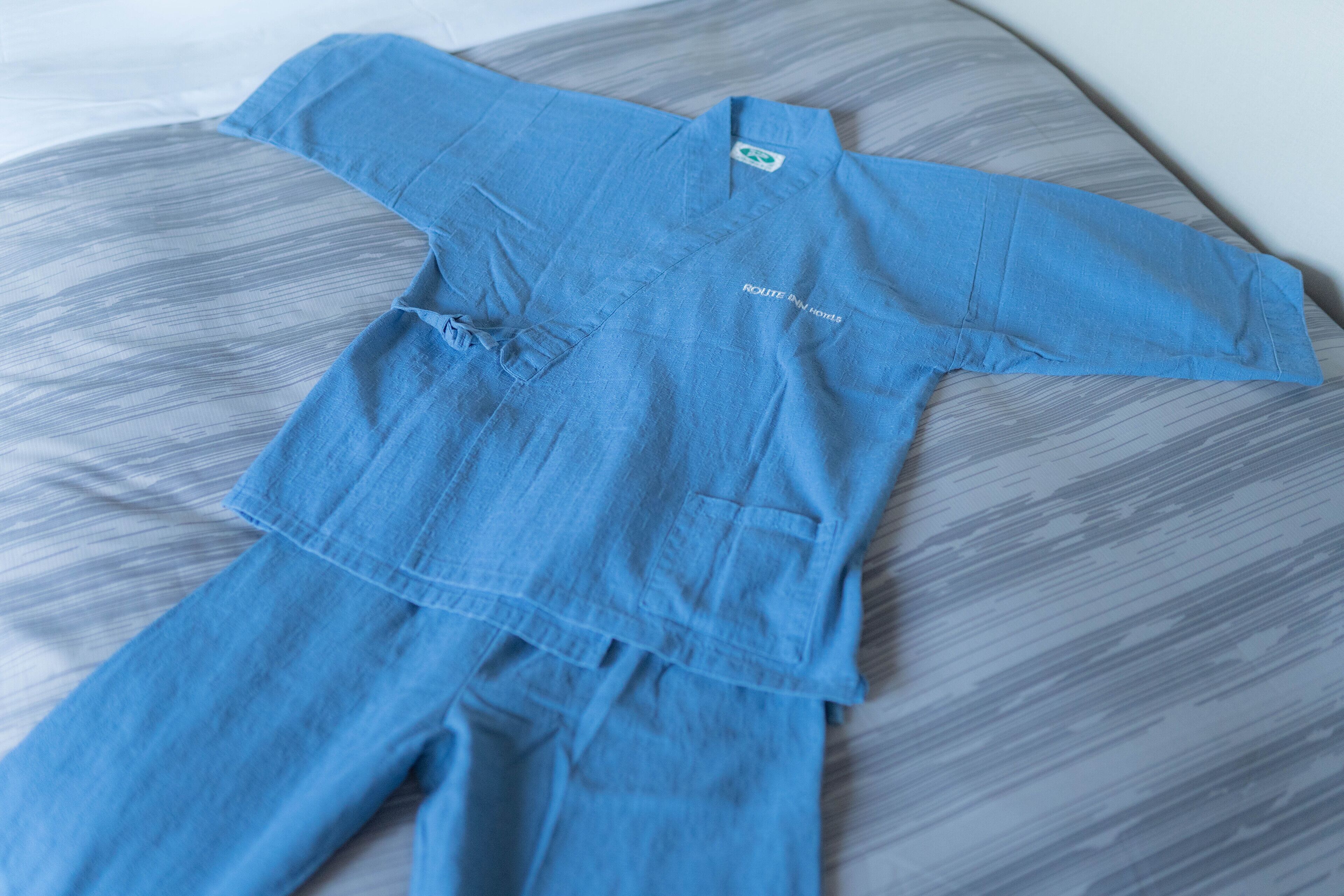 Ein blaues Outfit liegt auf einer gemusterten Fläche.