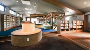 A library with bookshelves, a central reading area with a circular table, and a hammock. - Route Inn Grantia Tokai Spa & Relaxation (Tokai)