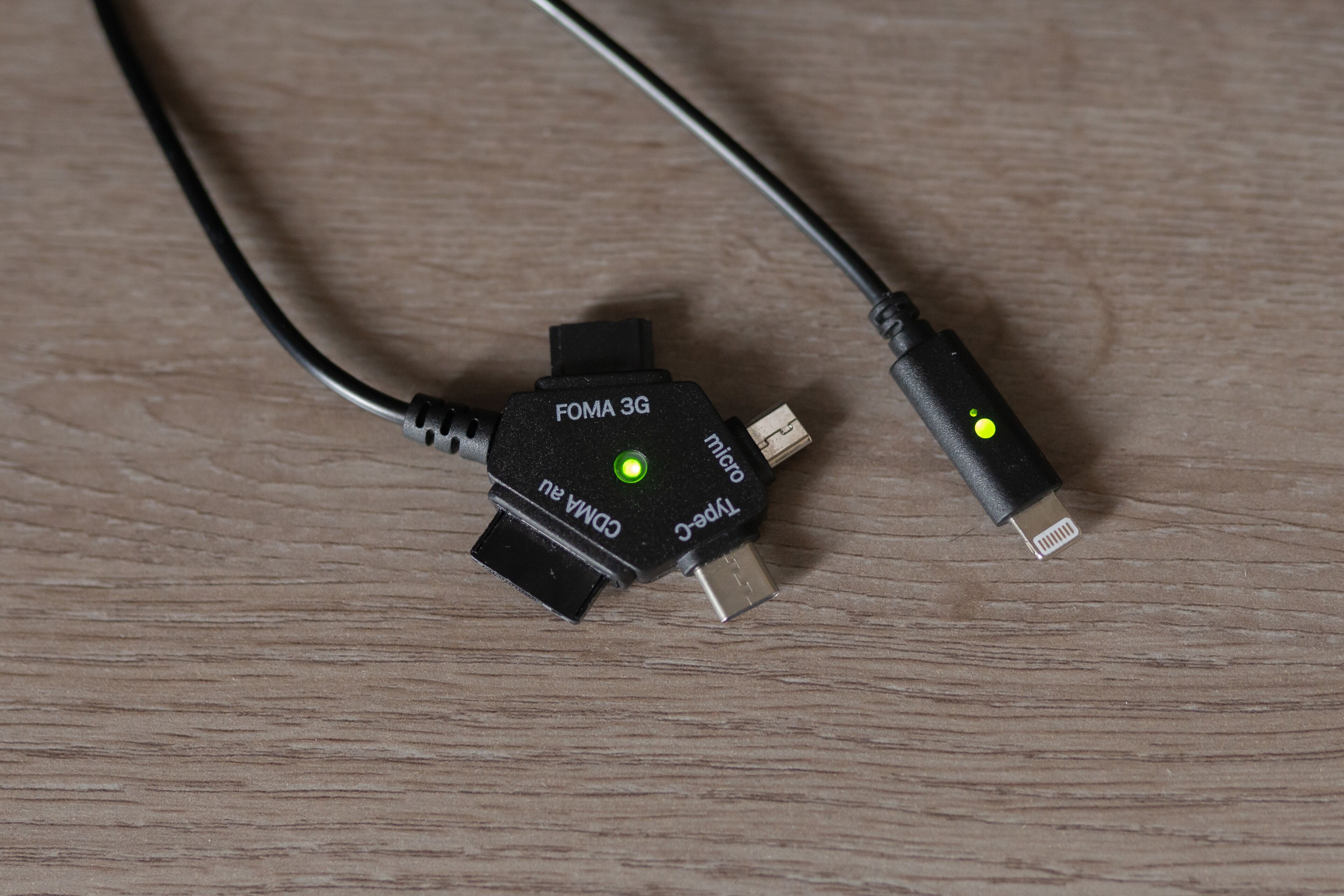 Un modem FOMA 3G avec un câble USB, posé sur une surface en bois.