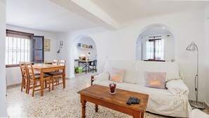 A living room with a sofa, coffee table, and dining area with chairs and a table. - La Piriposa Vélez-Málaga by Ruralidays (Málaga)