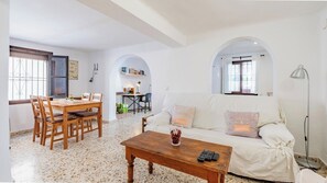 A living room with a sofa, coffee table, and dining area with chairs and a table.