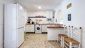 A compact kitchen with a washing machine, a sink, and a dining area with a bench. - La Piriposa Vélez-Málaga by Ruralidays (Málaga)