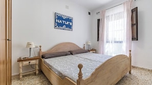 Una camera da letto con un letto in legno, due comodini con lampade, un cartello a parete e una finestra con tende.