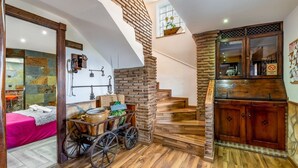 Ein rustikaler Innenraum mit einer Holztreppe, einem Wagen mit Küchenutensilien und einer Steinwand.