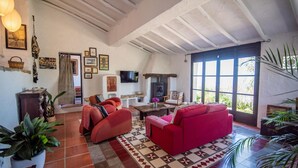 A spacious living room with a red sofa, a fireplace, and a large window offering a view of greenery.