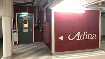 A hallway with a red wall featuring the name 'Adina' and directional arrows.