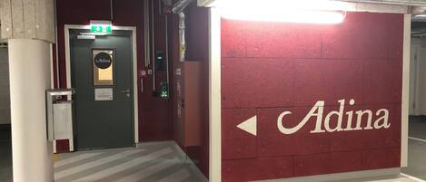 A hallway with a red wall featuring the name 'Adina' and directional arrows.