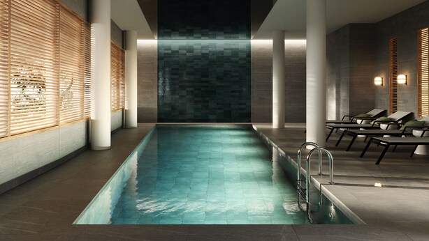 Una piscina interior moderna con vista despejada al área de la piscina, que incluye un espacio de descanso con sillones y piso de baldosas.