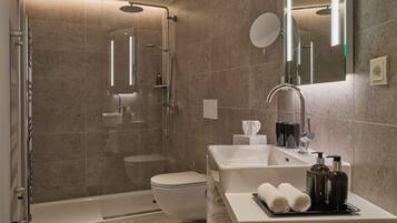 A modern bathroom with a glass-enclosed shower, a white toilet, a sink with a mirror, and toiletries on the counter.