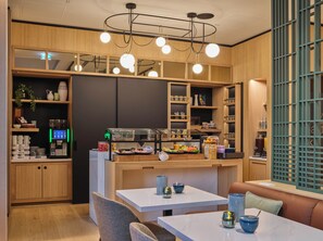 Ein modernes Café mit Holzausstattung, einer Kaffeemaschine und einem Selbstbedienungsbereich.
