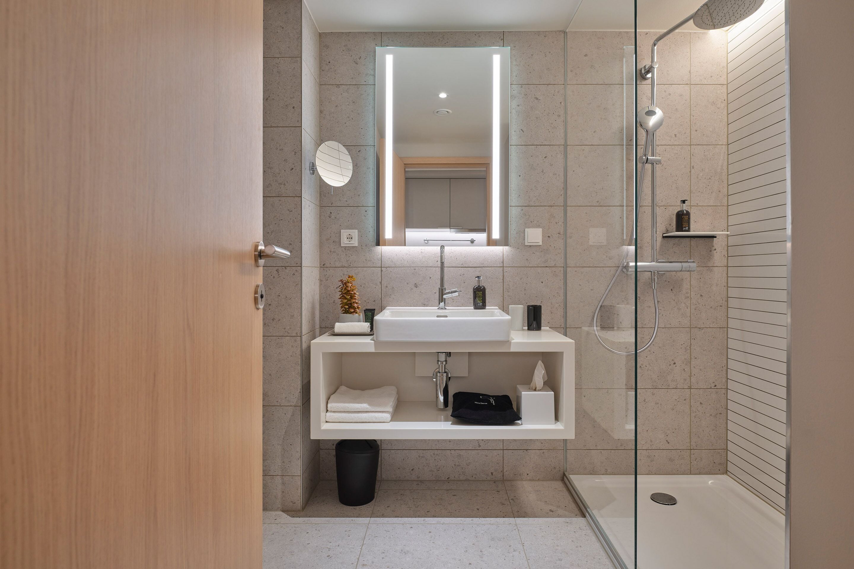 Un baño moderno con cabina de ducha de vidrio, un lavabo blanco y un espejo encima.