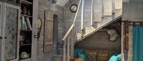 Et rustikt interiør med trævægge, en trappe, en sofa med puder og en tromme.