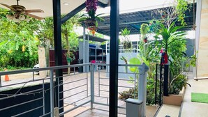 A modern indoor space with a glass table, a ceiling fan, and a variety of potted plants. - Baan Barrier (Pattaya)
