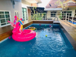 En pool med en rosa enhörningsformad badleksak och en stege.
