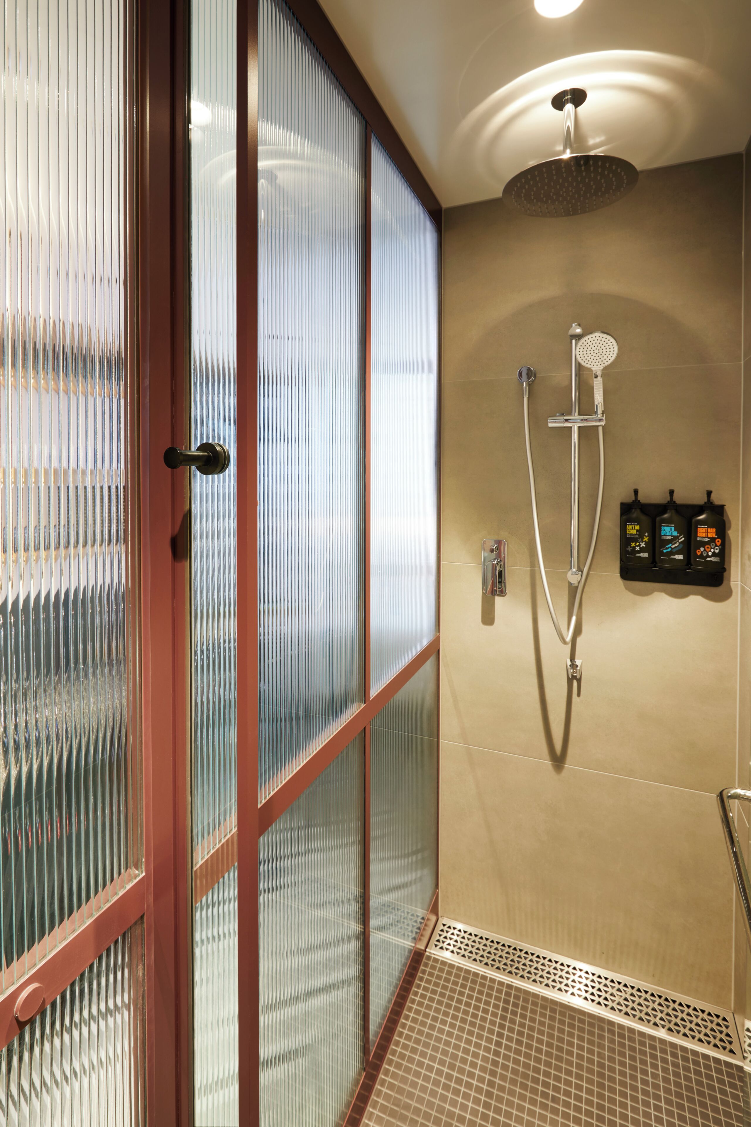 Une douche équipée d’un pommeau de douche à main, d’un robinet mural et d’un panneau de commande.