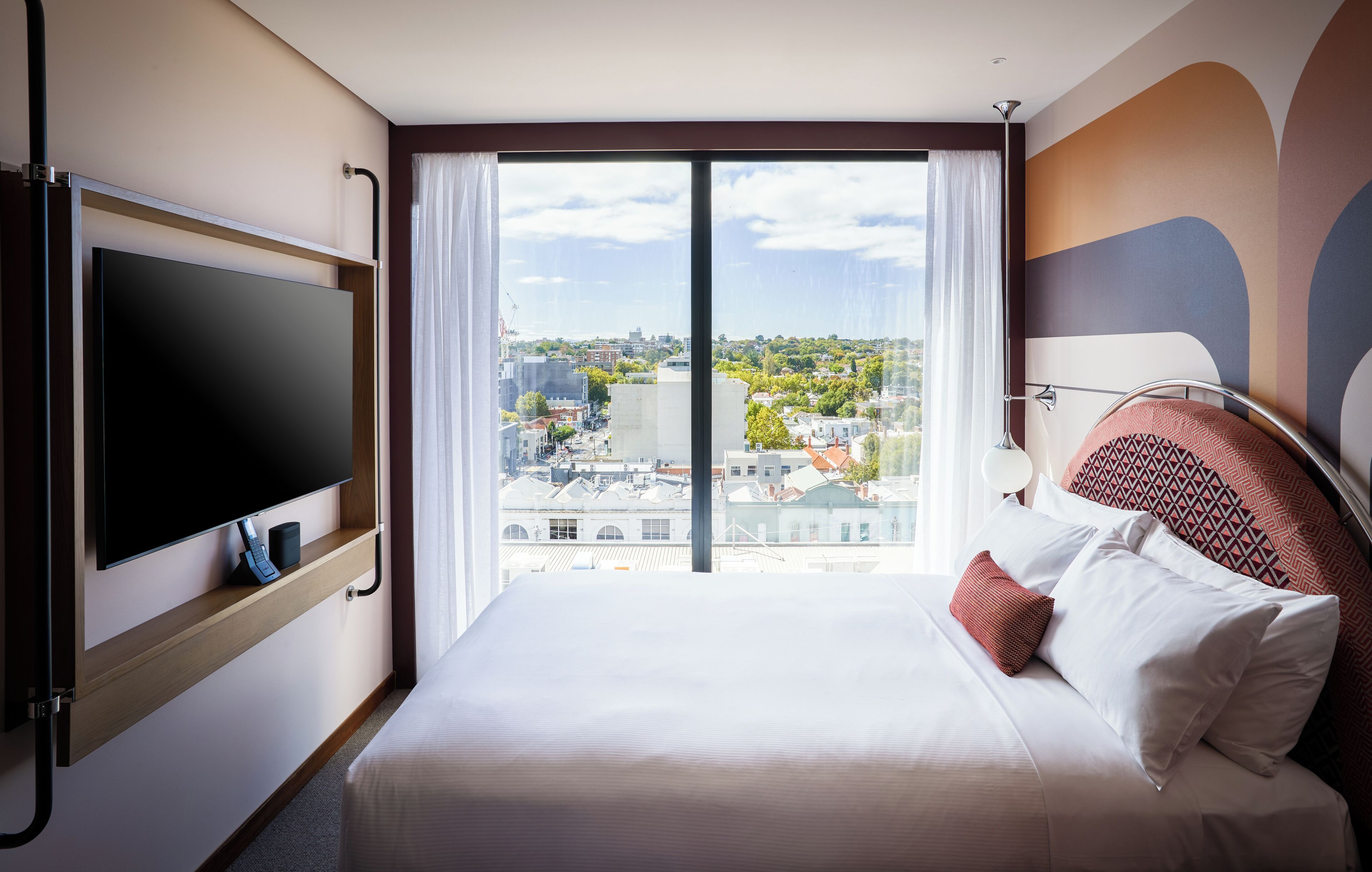 Habitación de hotel con una cama grande, televisión de pantalla plana, vista a la ciudad y diseño moderno.