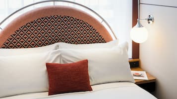 A bed with a headboard, pillows, and a bedside table with a lamp.