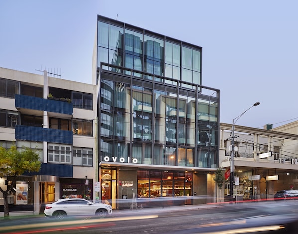 A modern building with a glass facade, a visible entrance, and a sign that reads "OVOLO".