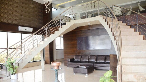 A modern interior with a staircase, a sofa, and a coffee table. - Hotel Sai Vijay (Nashik)
