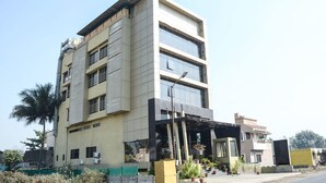 A multi-story building with a modern architectural design, featuring a mix of glass and metal elements, and a covered entrance area with potted plants. - Hotel Sai Vijay (Nashik)