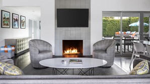 Una sala de estar moderna con chimenea, un televisor de pantalla plana y una mesa de centro redonda.