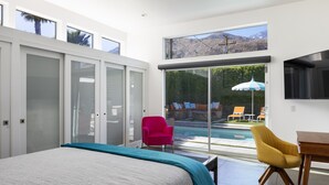 Un dormitorio moderno con una cama grande, un ventanal luminoso y vistas a una piscina.