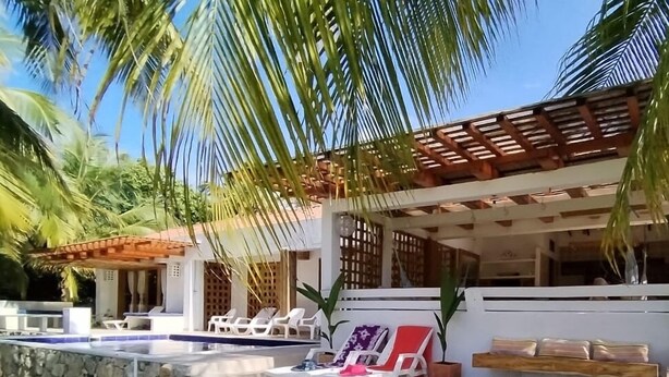 Un espace aménagé au bord de la piscine, avec des chaises longues, un mur en pierre et une pergola en bois.