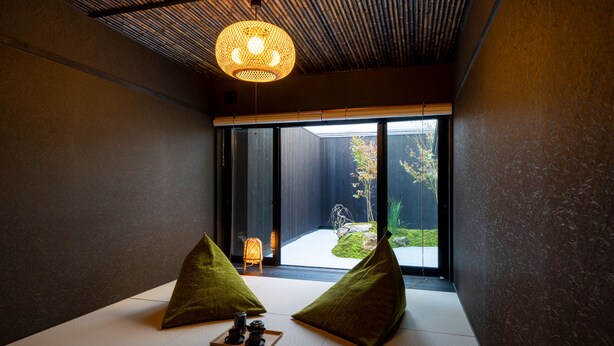A minimalist room with tatami flooring, two green cushions, and a traditional Japanese tea set on a tray. - Sanjusangendo Yoinotake (Kyoto)