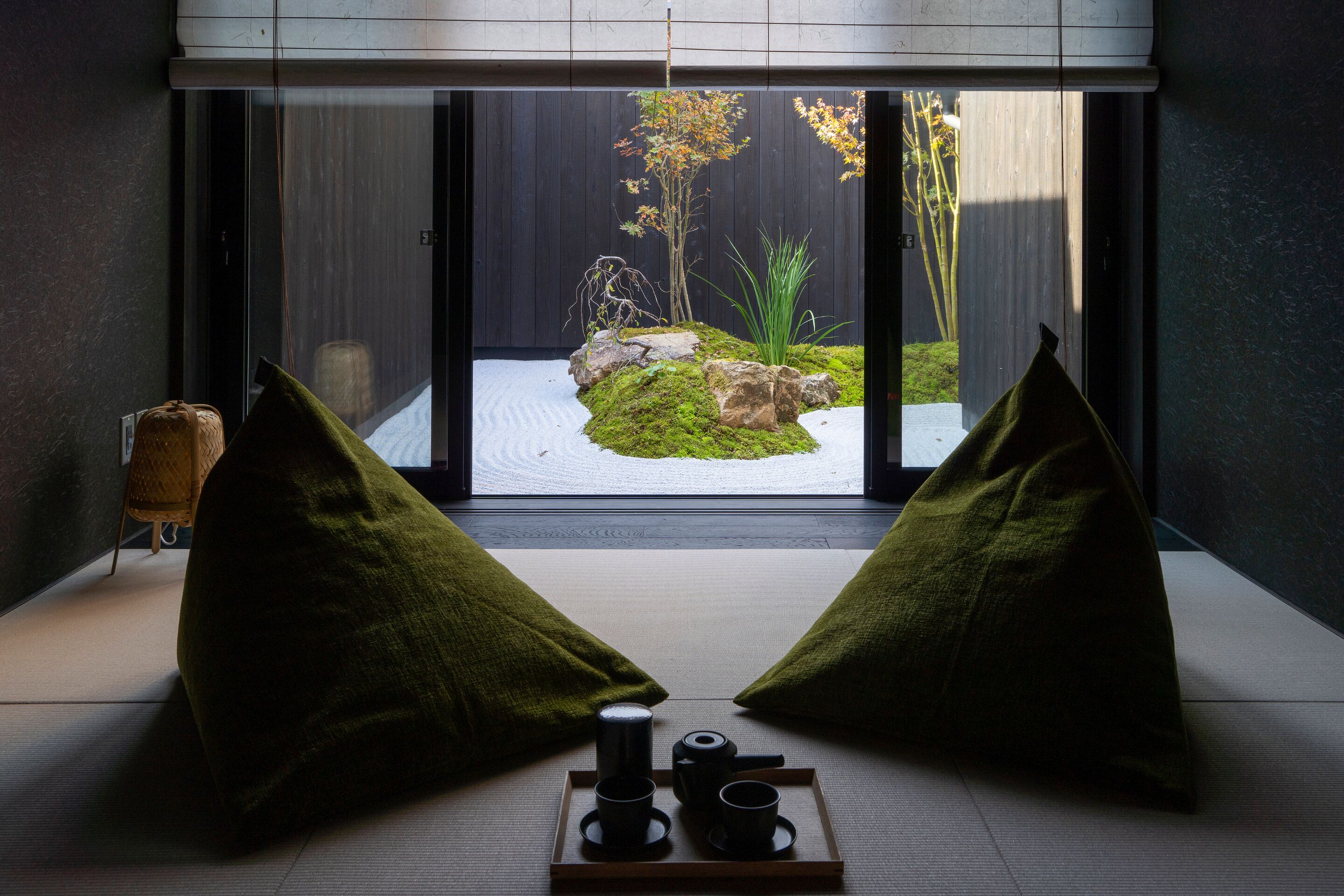 A room with tatami flooring, a sliding glass door leading to a garden, and a tray with tea utensils.