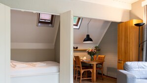 Une pièce compacte comprenant un lit en mezzanine, un coin repas avec une table et des chaises, et un canapé.