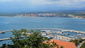 Un port de plaisance avec des bateaux amarrés, une vue sur la ville côtière en arrière-plan et un ciel dégagé.