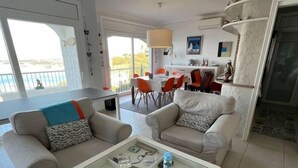 Un salon moderne avec deux canapés, une table basse et un coin repas avec des chaises rouges.