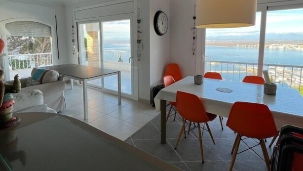 Un salon moderne avec un coin repas, de grandes fenêtres et une vue sur la mer.