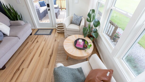 Una sala de estar acogedora con sofá, sillón y mesa de centro. Un ventanal corredizo da a un patio exterior con mesa y sillas.