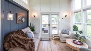 Una sala de estar acogedora con un sofá, una mesita de centro y vistas a una terraza exterior a través de un ventanal.