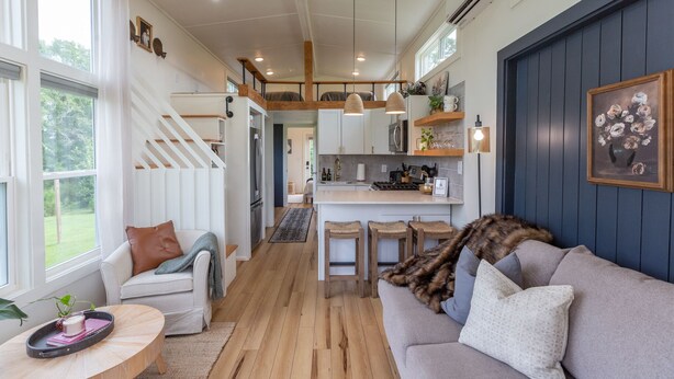 Una cocina moderna con una isla central, taburetes de madera e iluminación colgante.