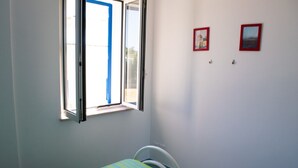 A room with a bed, a window, and two framed pictures on the wall. - Il Carrubo bright and fresh apartment with beautiful view (Marina di Novaglie)
