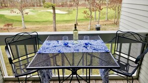 A patio with a table and chairs, overlooking a golf course.