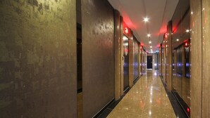 A corridor with reflective flooring, wooden columns, and red ambient lighting. - Hotel Lesign (Busan)