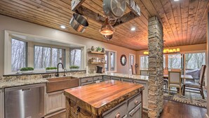 Un'ampia cucina con una grande isola, travi in legno al soffitto e una colonna in pietra.
