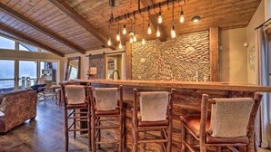 Un interno rustico con parete in pietra, soffitto in legno e sgabelli da bar.