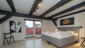 Un dormitorio con cama, ventana, un cuadro y una escalera.